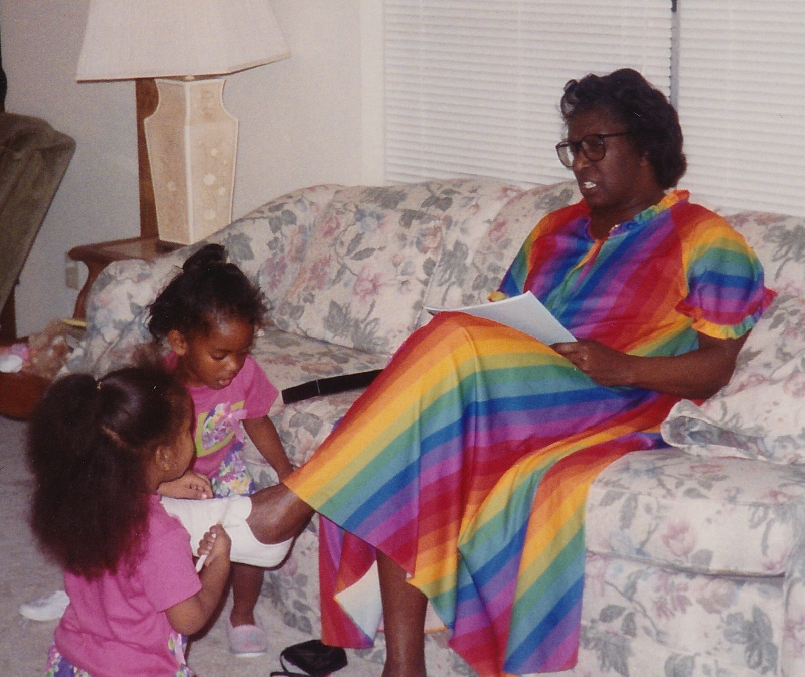 Annie Will Bell Gatlin reading aloud on the couch, two little girls playing at her feet